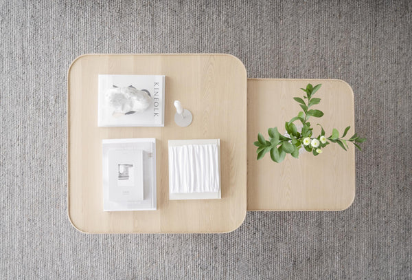 Ljusa träsoffbord med rundade hörn i skandinavisk design, dekorerade med böcker och grön växt ovanifrån