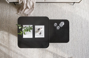 Svarta soffbord i trä med rundade hörn, dekorerade med tavlor och glas, på ljus matta i vardagsrum