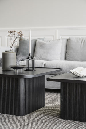 Svarta soffbord med räfflad design och ljusgrå soffa i modern skandinavisk vardagsrumsinredning