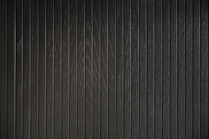 Svart träpanel med vertikal trästruktur och synliga naturliga åringar i mörk nyans