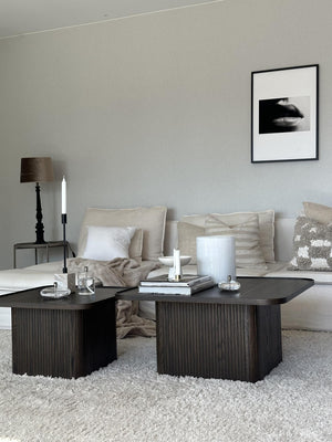 Mörkt soffbord med räfflad design i vardagsrum med beige soffa och ljus inredning