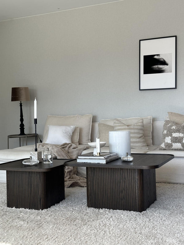 Mörkt soffbord med räfflad design i vardagsrum med beige soffa och ljus inredning