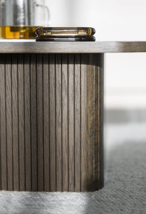 Soffbord med räfflad träfot i grått trä och ljus träskiva, dekorerat med glasföremål och gul vas