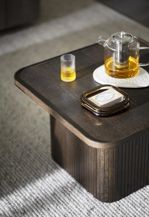 Soffbord i mörkt trä med glas tepanna, tekop och bricka på vit matta