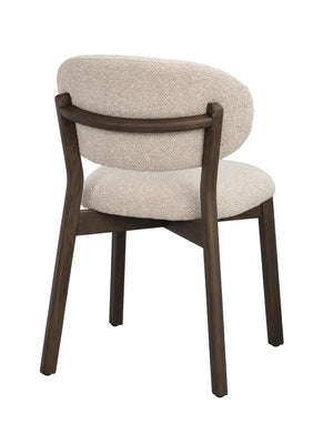 Matstol med beige klädsel och mörkbruna träben, sedd från sidan mot vit bakgrund