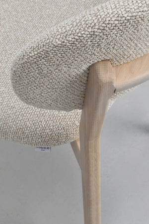 Närbild av beige stoppad stol med träben och vävd textilklädsel från Rowico