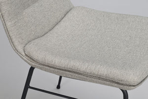 Närbild på sits i ljusgrå textil med svarta metallben på stol