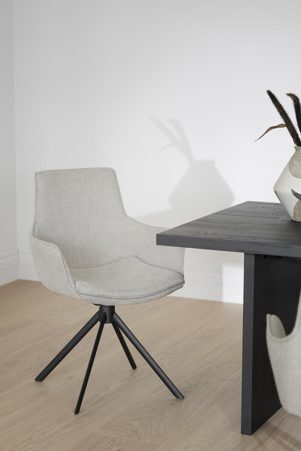 Grå stol med hög rygg och svart trepunktsfot i modern design