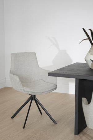 Grå stoppad matstol med svart metallstativ vid mörkgrått matbord i minimalistisk miljö