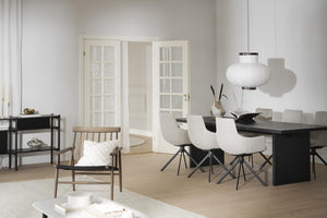 Minimalistisk matplats med svart matbord, vita stolar och vit taklampa i skandinavisk stil