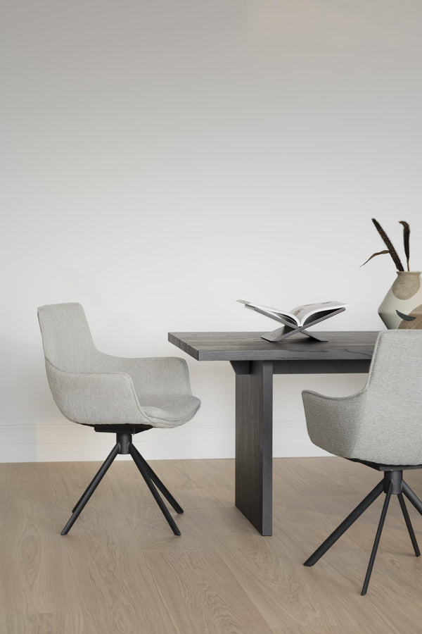 Grå matstolar med svart spindelben vid matbord i modern skandinavisk design