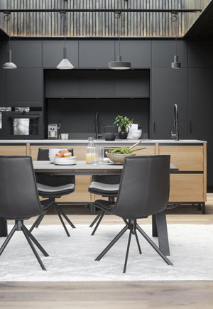 Modernt kök med grå skåp, trädetaljer och matbord med svarta stolar i skandinavisk design