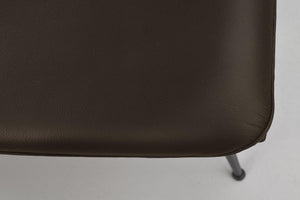 Närbild på mörkbrunt lädersits med synlig textur och metallben på möbel