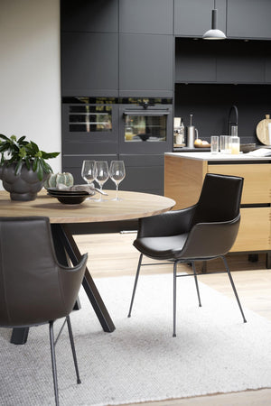 Modernt kök med grå skåp, ljust trädiningbord och svarta stolar i skandinavisk design