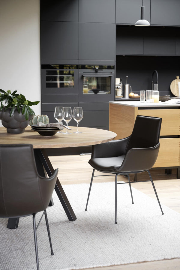 Modernt kök med grå skåp, ljust trädiningbord och svarta stolar i skandinavisk design