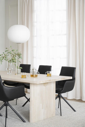 Matbord i ljust trä med svarta stolar i modern skandinavisk matsal med fönster och pendant lampa