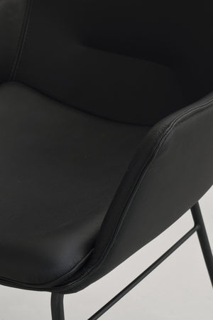 Närbild på svart läder matstol med mjukt stoppad sits och metallben