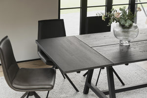 Utdragbart matbord i mörkgrått trä med svarta ben och matchande stolar i modernt skandinavisk design