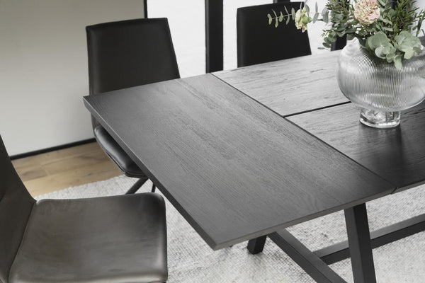 Gråt utdragbart matbord med trästruktur och svarta stolar i modern matsal