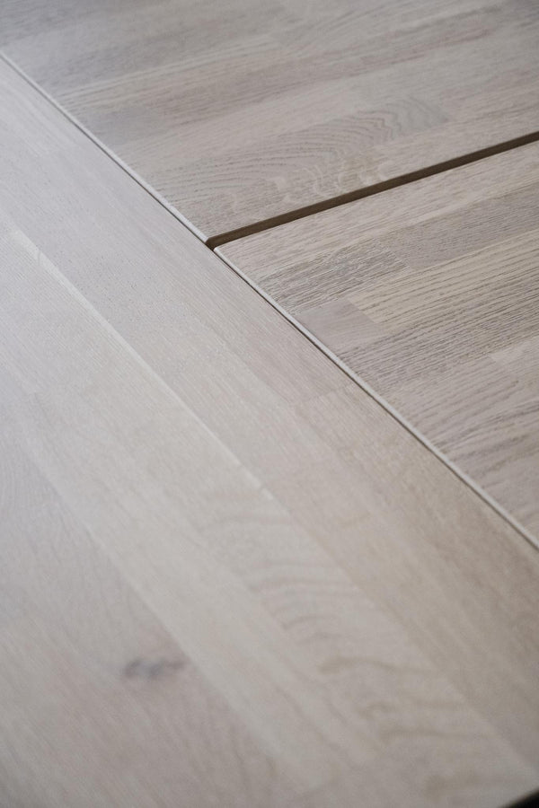 Ljust laminatgolv i ekdekor med synliga skarvar och naturlig trästruktur i närbild