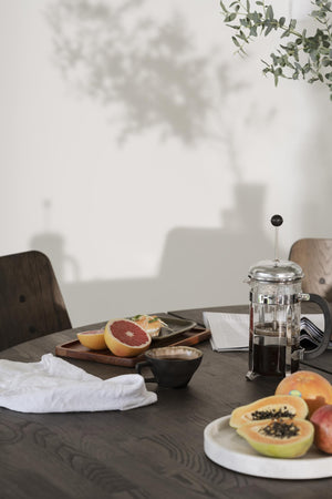 Frukostbord med French press-kaffebryggare, färsk frukt och kaffekopp i minimalistisk stil