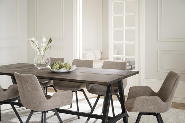 Matgrupp med grå stoppade stolar och bord i mörkt trä med svarta ben i ljus matsal