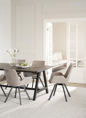 Matbord i grå ek med svarta ben omgivet av beige stoppade stolar i modern skandinavisk stil