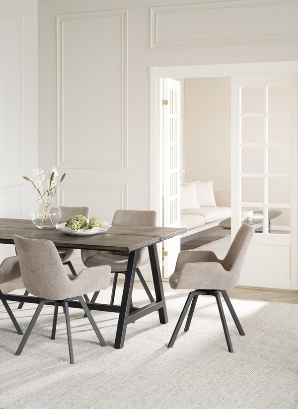 Matbord i grå ek med svarta ben omgivet av beige stoppade stolar i modern skandinavisk stil