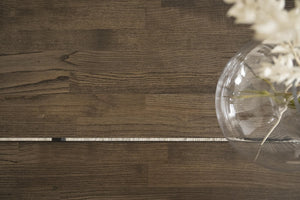 Mörkbrunt trägolv i ek med glasvas och vita blommor på genomskinligt bord