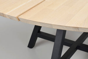 Närbildsvy av bordsskiva i ljust trä med synlig fог och svart metallunderrede