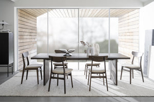 Matbord i mörkt trä med sex stolar och vita klädselstoppade sitsar i modern skandinavisk matsal