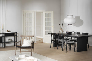 Minimalistisk matsal med svart matbord, stolar och vit pendellampa i skandinavisk stil