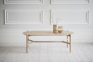 Ovalt soffbord i ljust trä med skandinavisk design, dekorerat med vaser på ljus matta