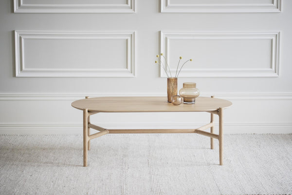 Ovalt soffbord i ljust trä med skandinavisk design, dekorerat med vaser på ljus matta