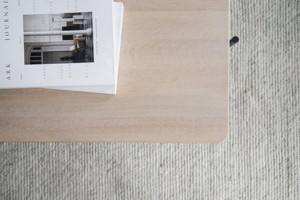 Ljust träbord med inredningsmagasin på ljusgrå randig matta