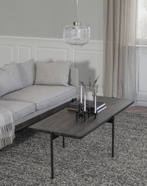 Modernt vardagsrum med grå soffa, svart soffbord med träskiva och glaspendel ovanför