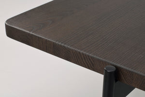 Närbild på mörkbrun träskiva med träfibermönster och svart metallben i hörnet