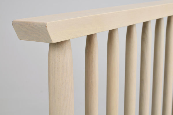 Närbild på ljust trä möbeldetalj med spjälor och rundad överlist i naturlig bokfärg
