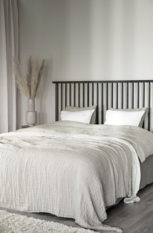 Sovrum med vit sängkläder i linne, svart spjälsäng och beige dekoration i minimalistisk stil