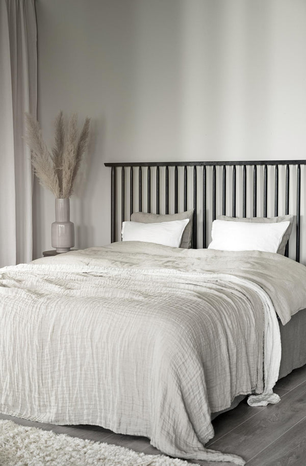 Sovrum med vit sängkläder i linne, svart spjälsäng och beige dekoration i minimalistisk stil