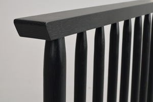 Närbild av svartbetsad träräcke med runda spjälor och rektangulär handledare i modern design