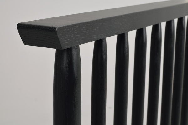 Närbild av svartbetsad träräcke med runda spjälor och rektangulär handledare i modern design