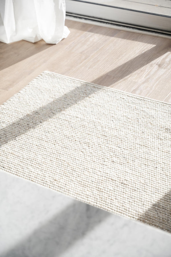 Vit textilmatta på ljust trägolv med beige och grå nyanser, perfekt som hallmatta eller badrumsförlägare