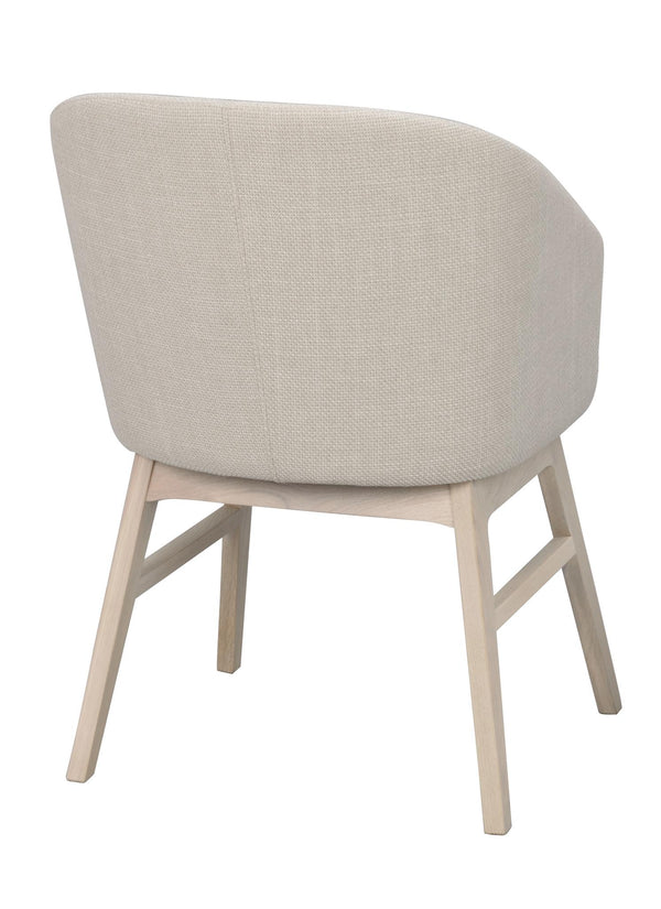 Beige fåtölj med rundad rygg och ljusa träben, sedd från sidan mot vit bakgrund