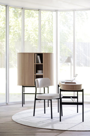 Ljust arbetsrum med skrivbord, stol och skåp i ek och svart metall framför stora fönster med trädgårdsvy