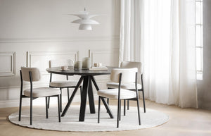 Rund matgrupp med svart bord och fyra beige stolar i modern matsal med vit inredning