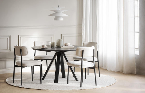 Rund matgrupp med svart bord och fyra beige stolar i modern matsal med vit inredning