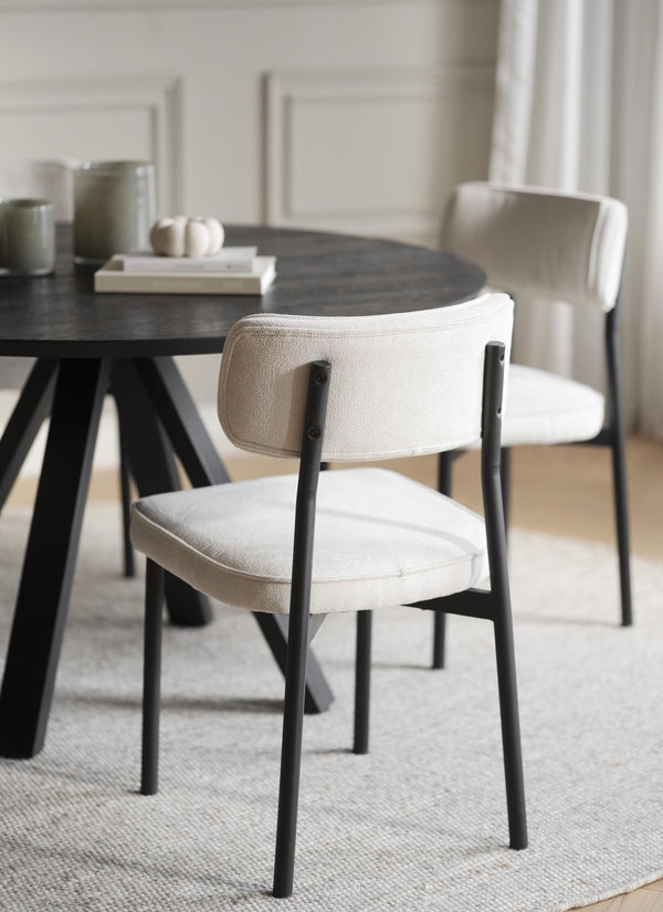 Matbord i svart trä med vita stoppade stolar i linnefärgat tyg och svarta ben i modern matsal