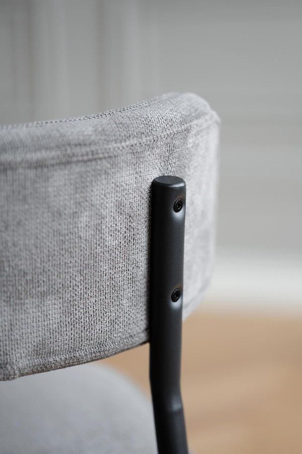 Närbild på grå stoppning och svart metallram på modern stol med minimalistisk design