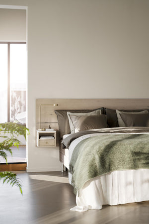 Sovrum i skandinavisk stil med ljus träsäng, gröna textilier och luftig känsla genom öppen dörr
